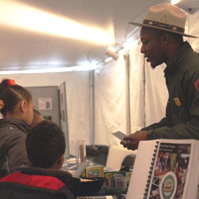 Three young people and an adult talk to a Ranger about Junior Ranger activities.