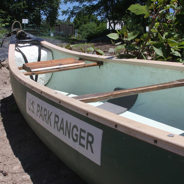 low angle view of canoe with green shell, white interior. Text on side reads 