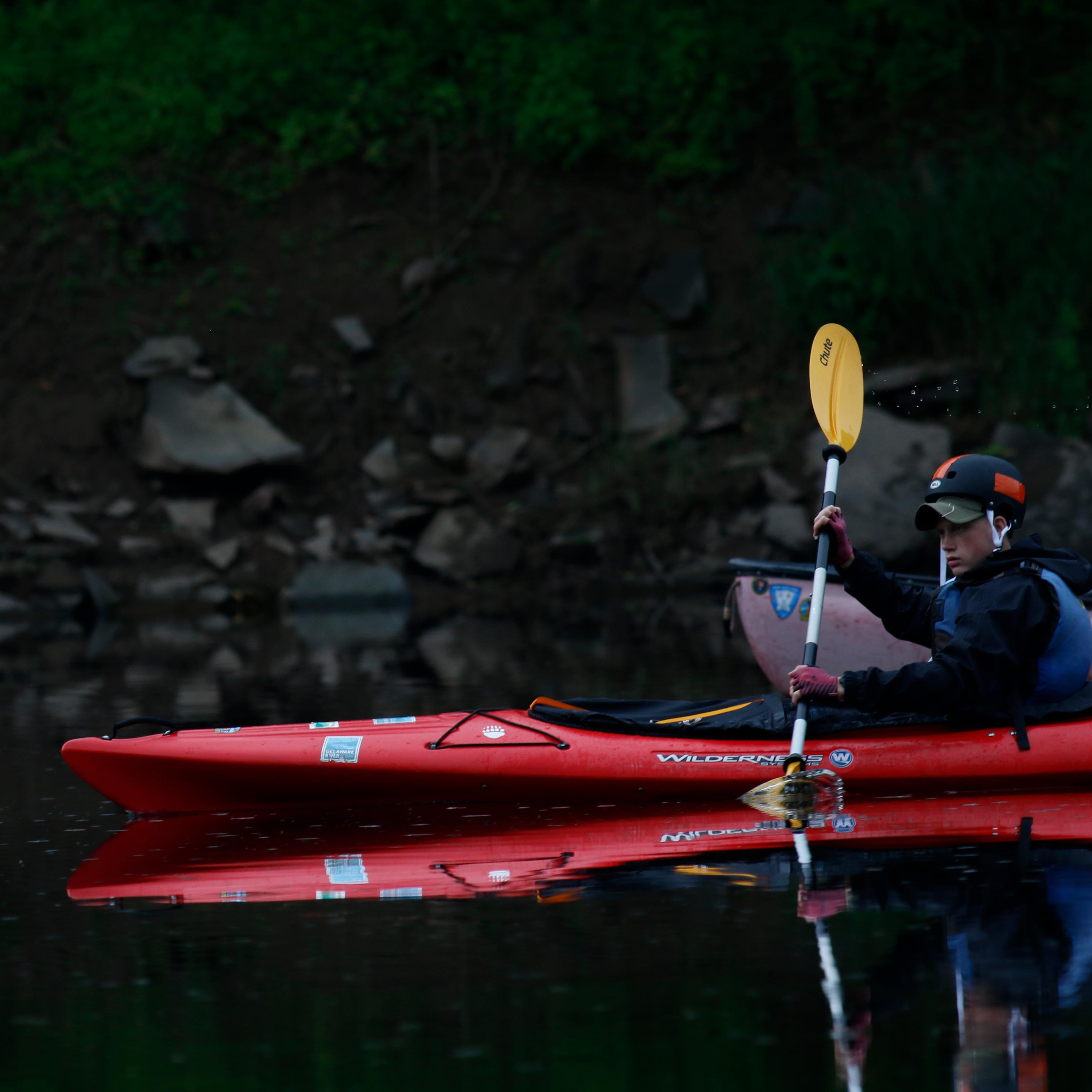Young boy in kayak cuts through the water.