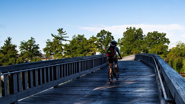 Bicyclist crossing a wooden bridge over a river channel