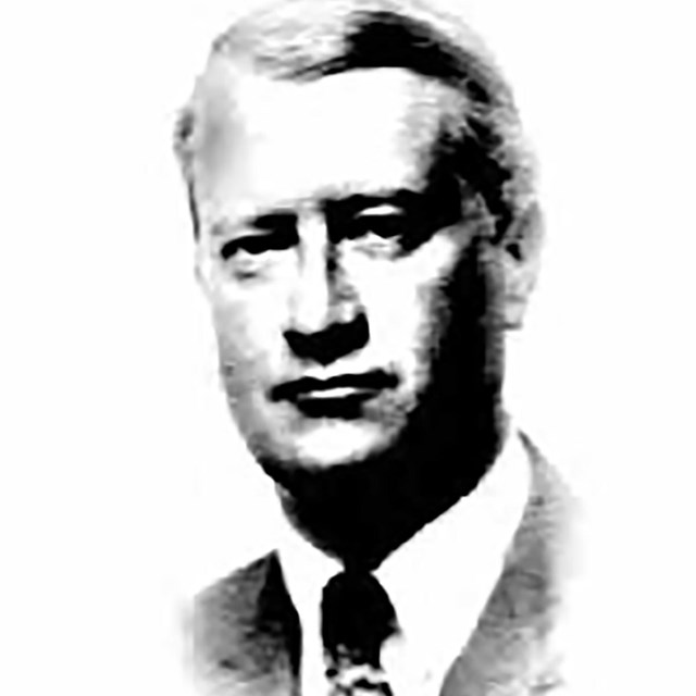 A head and shoulders portrait of a man wearing a coat and tie.