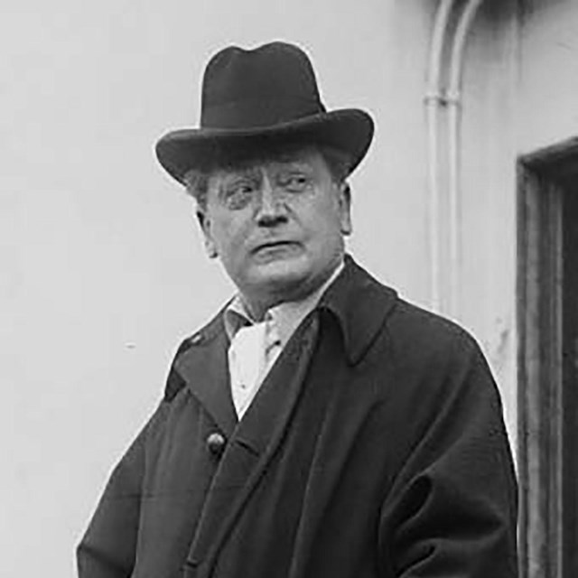 A man wearing a dark hat and coat.