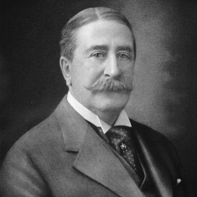 A head and shoulders portrait of a man in a suit.