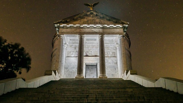 The Illinois Monument illuminated from the inside at night. 