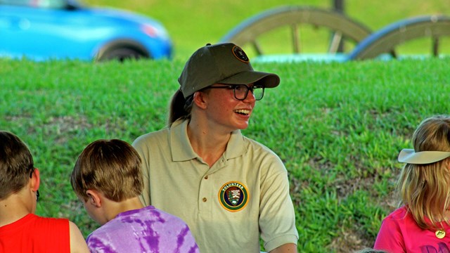 A park volunteer smiles at children at an outreach event