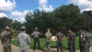 A park ranger discussing the military operations during the Vicksburg Campaign to seven soldiers.