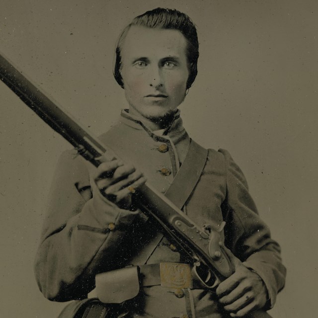 A Confederate soldier from Louisiana holding a musket across his body.