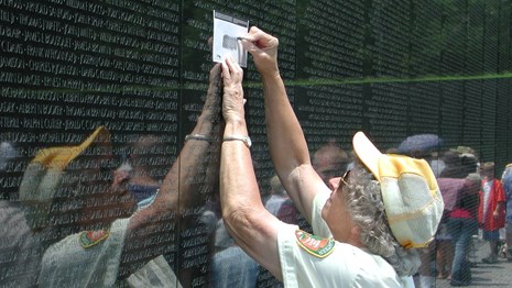 Volunteer taking a rubbing of a name on the Vietnam Veterans Memorial