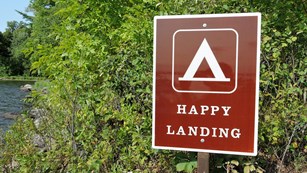 A brown sign with a tent symbol labeled 