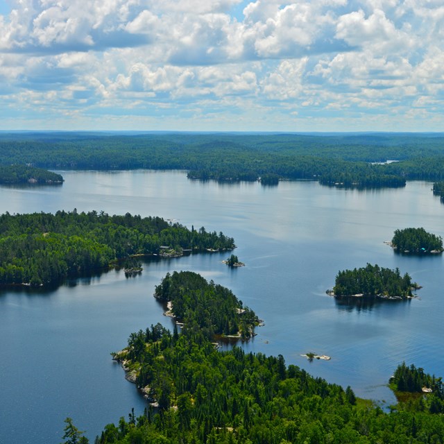 Several dark green islands--seen from above--dot a large scenic lake.