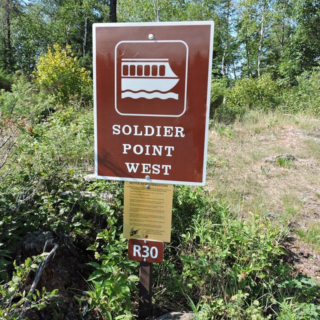A brown sign with a white houseboat symbol labeled 
