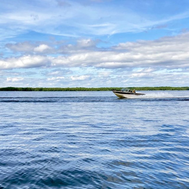 A motorboat speeds across the waters of a scenic blue lake.