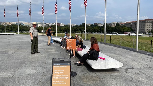 People sitting on a bench waiting to go into the Washington Monument