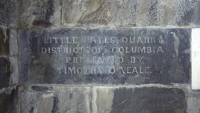 Stone sign reading "Little Falls Quarry"