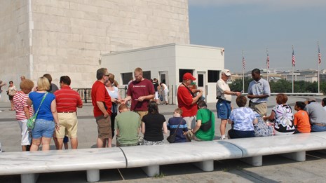 People sitting on a bench waiting to go into the Washington Monument
