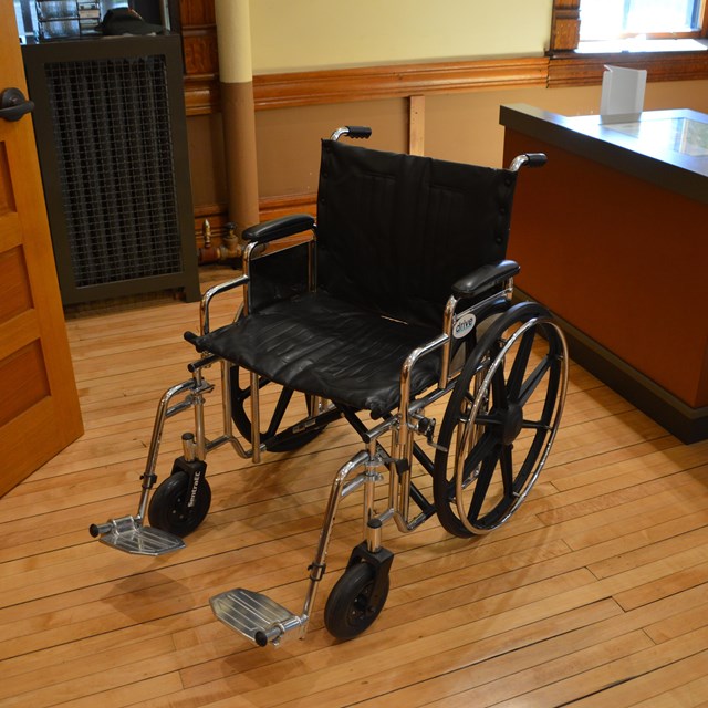 An empty wheelchair next to a desk.
