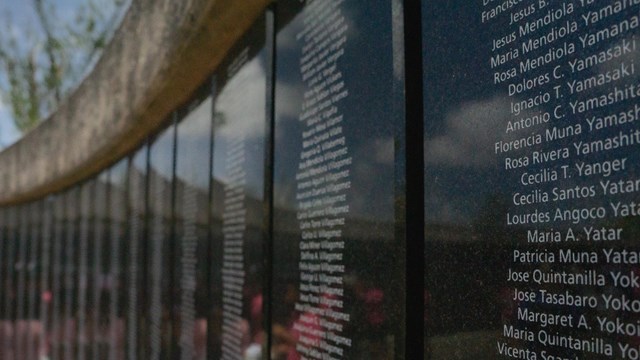Close up shot of a curved wall covered in black plaques with names engraved on them.