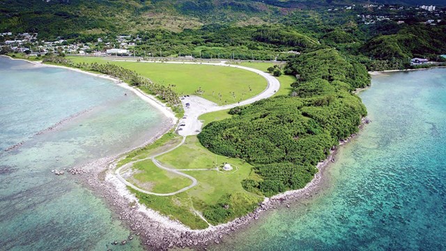 A point of land stretching out into the ocean. The right side of the point is heavily forested.