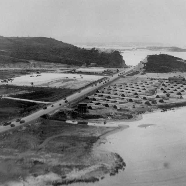 Military encampment with a highway running through it. The highway is full of military vehicles.