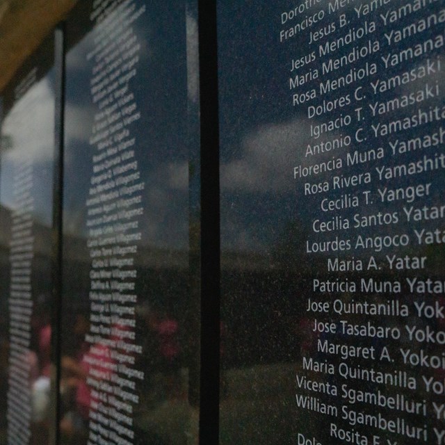 Close up shot of a curved wall covered in black plaques with names engraved on them.