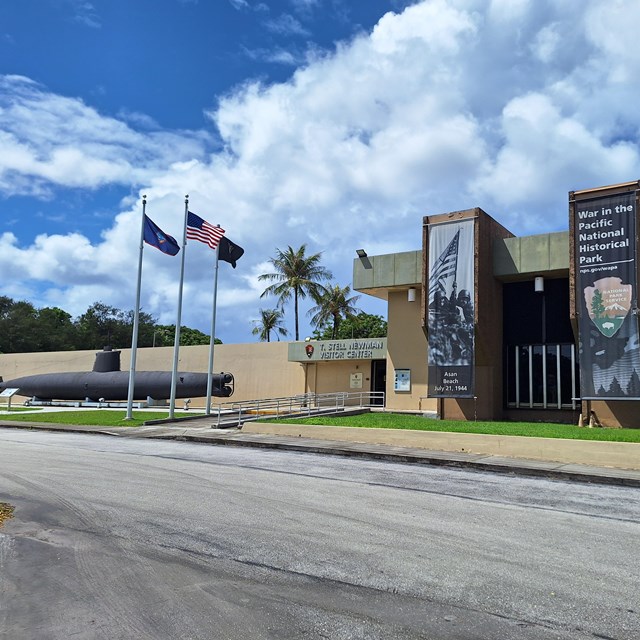A large building with a sign saying T. Stell Newman Visitor Center with a submarine in front.