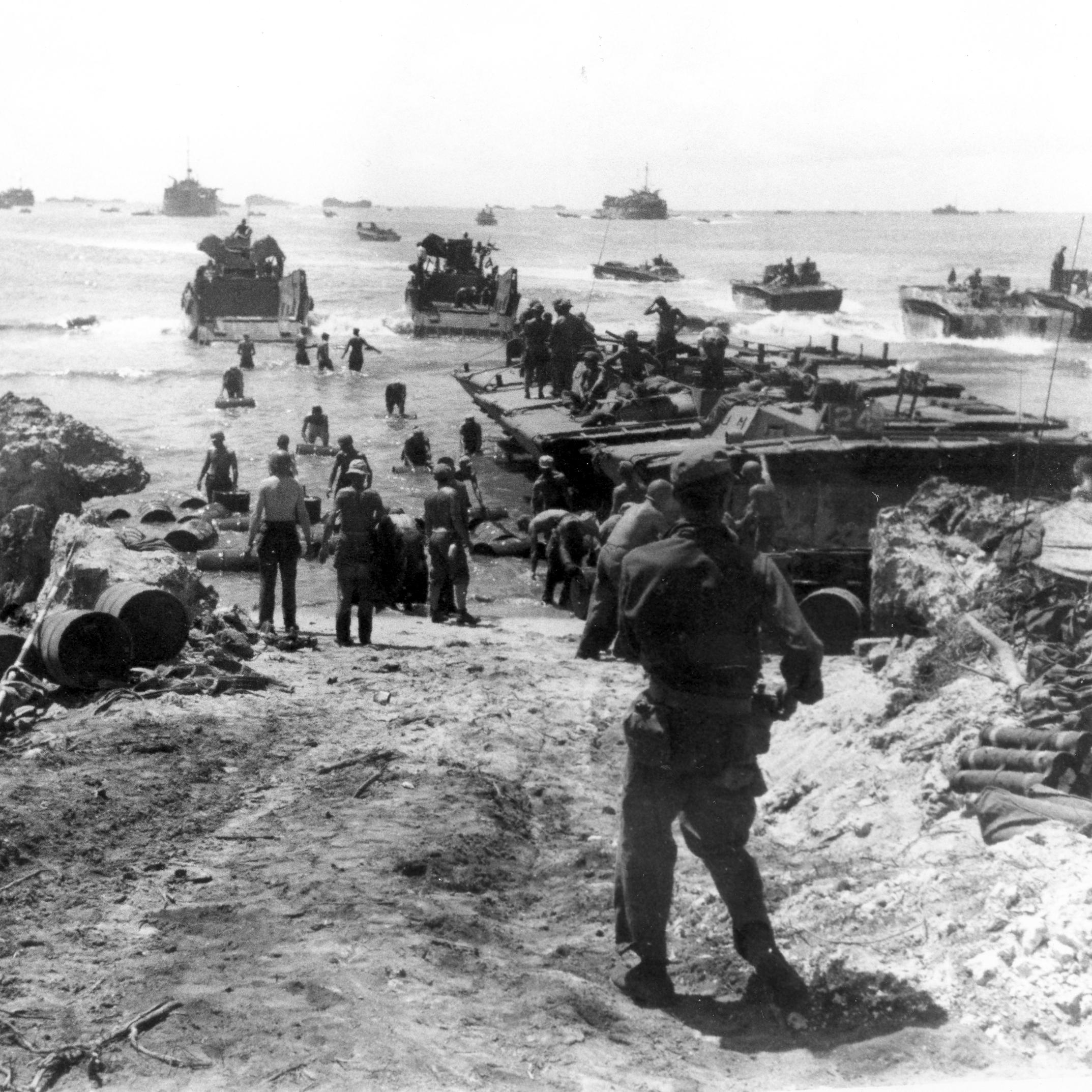 Soldiers unloading barrels of fuel from amtracs to the beach
