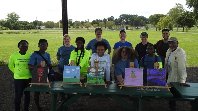 A group of people standing in front of a pond on a sunny day.