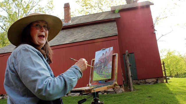 Painter holding a brush and smiling, while painting a red studio