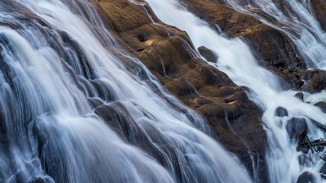 a waterfall streams down a rocky slope