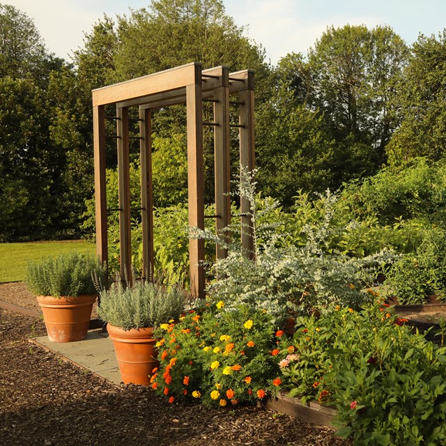 A square arch stands at the entrance of a vegetable garden.
