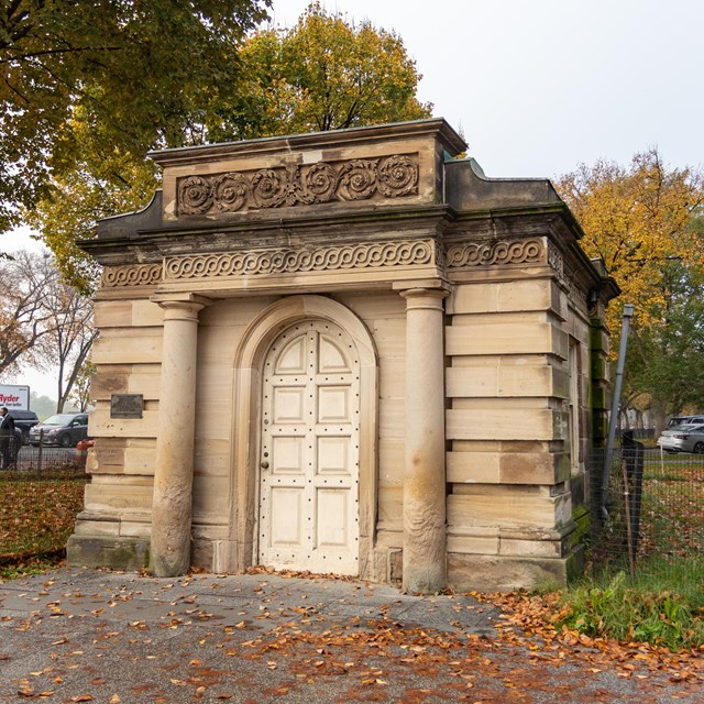 A cube-shaped stone building with an impressive door.