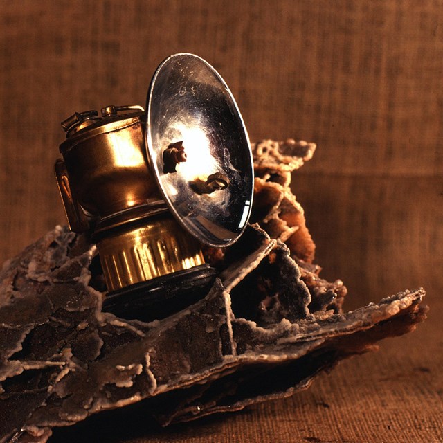 a carbide lamp sitting on a honeycomb shaped cave formation