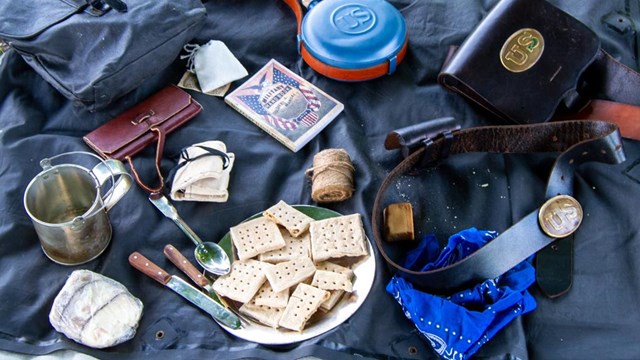 Volunteer stands on the Ray house's porch talking with his hands. 