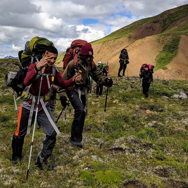 A group of hikers hike off-trail.