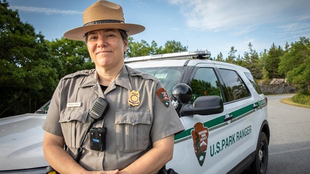 A woman in NPS uniform stands in front of an NPS truck.