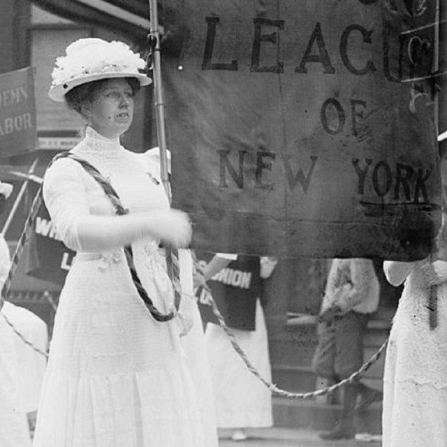 Woman dressed in white holding a banner.