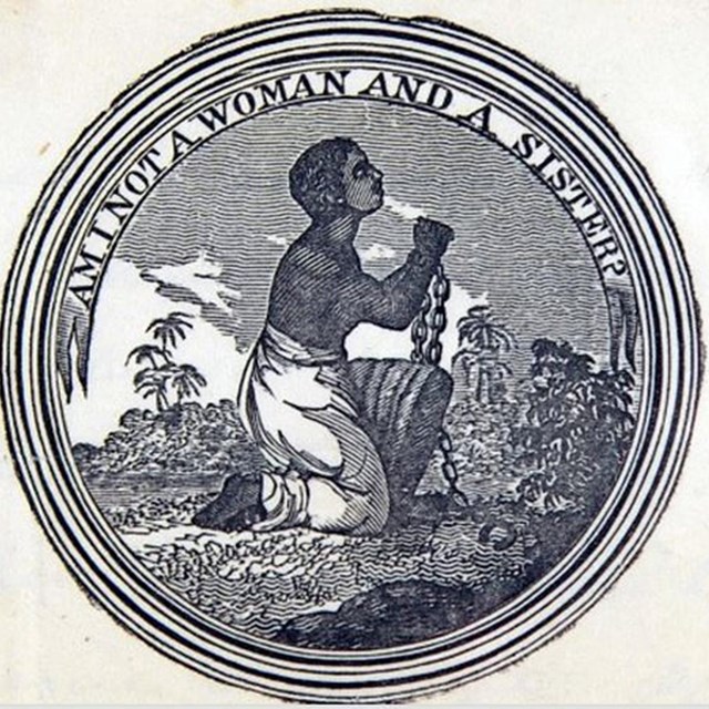Medallion of a black woman kneeling. Her hands are in bondage. Text: 