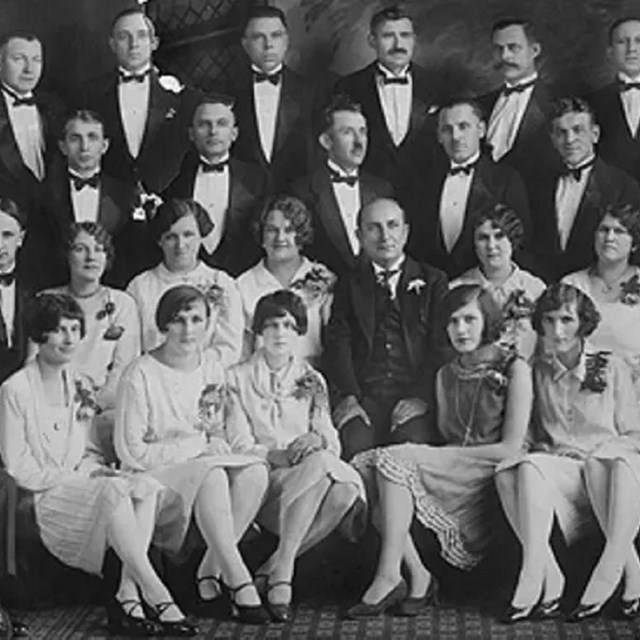 Group of people, women dressed in white and men in tuxedos