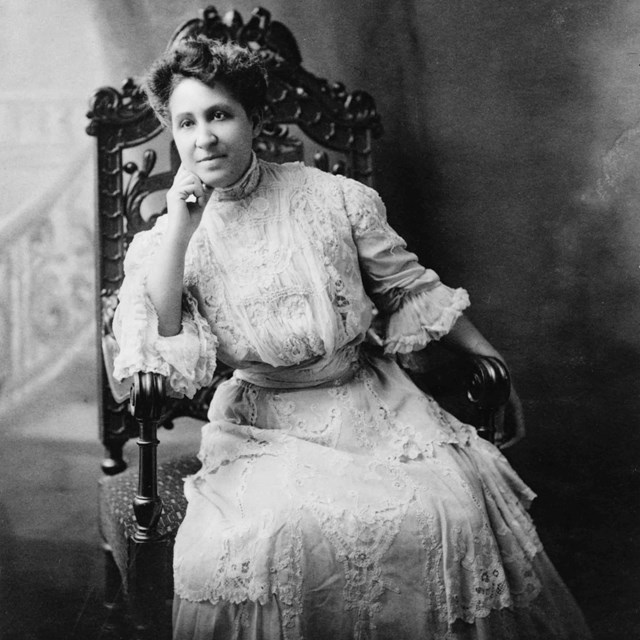 Woman wearing white dress seated in chair