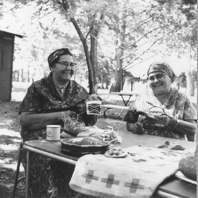 Two women with weaving equipment smiling