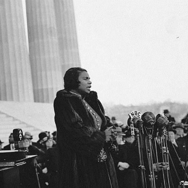 African American woman wearing fur coat singing outside building