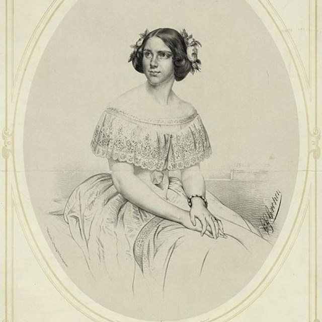 Woman with curled hair seated and wearing gown