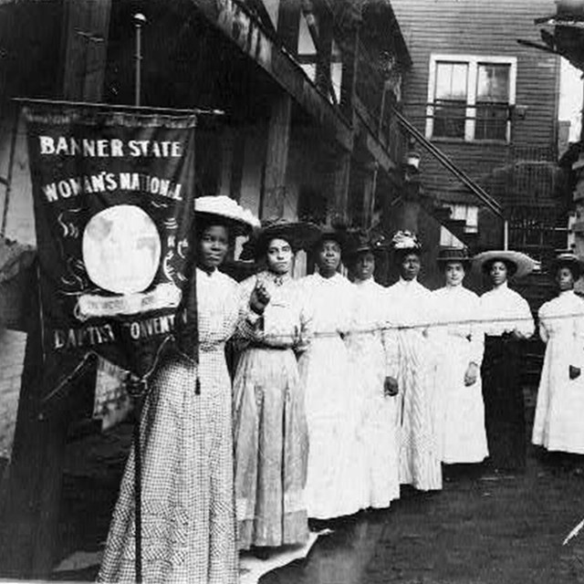 Nannie Helen Burroughs and other women holding a suffrage banner. LOC photo