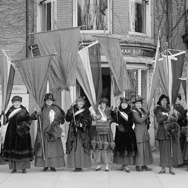 1910s women's suffragists standing holding banners. Library of Congress photo. 