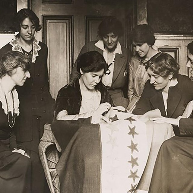 Alice Paul sews a star on the suffrage flag