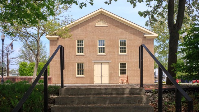 A view of a two-story brick building, looking up a set of stone stairs.