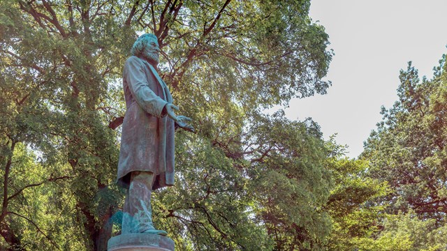 A statue of Frederick Douglass in front of trees.