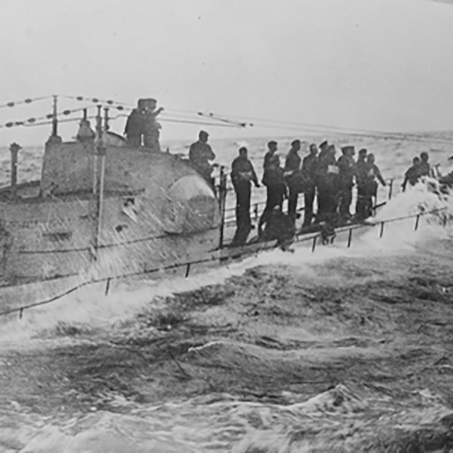 German submariners stand on the deck as waves crash around them.