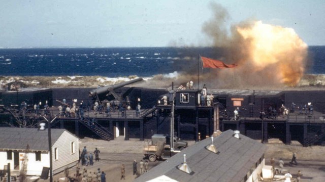colorized photo of artillery firing atop a fort wall