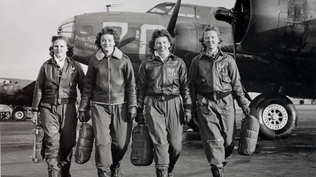 Photo of 4 female air force pilots wearing bomber jackets walking towards the cameraa